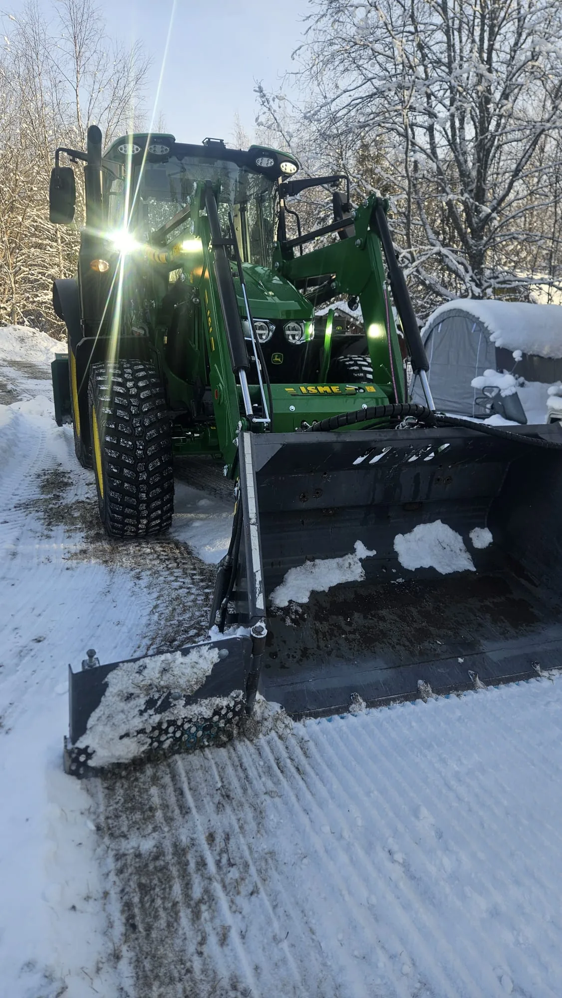 Talvikunnossapito – John Deere -traktori lumitöissä aurinkoisena päivänä