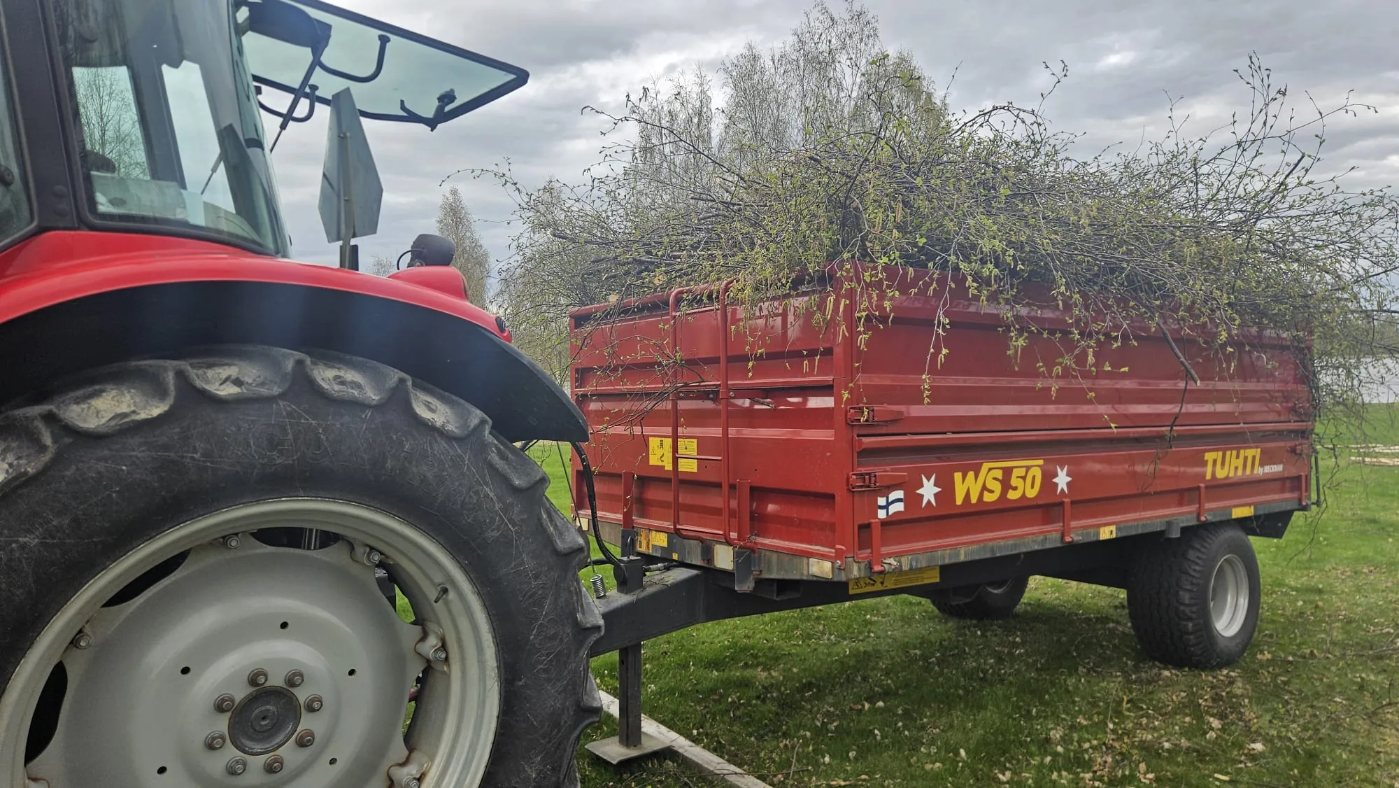 Traktori ja peräkärry täynnä oksia – oksa- ja risujätteen kuljetus