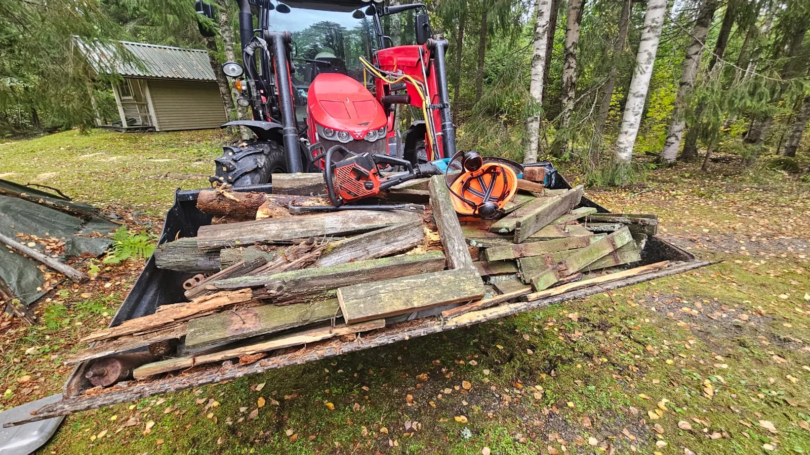 Vanha puumateriaali traktorikauhassa – piha-alueen siivous